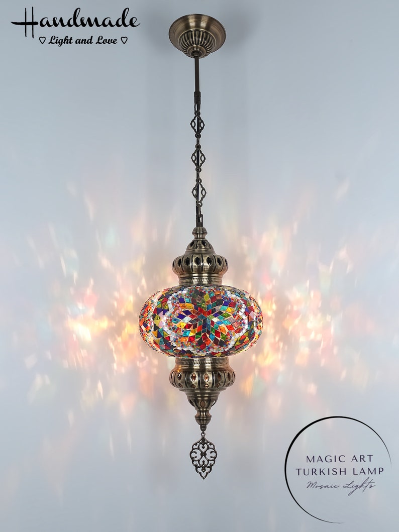 May include: A colorful mosaic Turkish lamp with a brass finish and a decorative chain hanging from the ceiling. The lamp is lit and casting a warm glow. The text "MAGIC ART TURKISH LAMP Mosaic Lights" is visible in the lower right corner of the image.