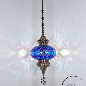 May include: A blue and green mosaic Turkish lamp with a brass chain and ceiling mount. The lamp is lit and casting a warm glow. The text "MAGIC ART TURKISH LAMP Mosaic Lights" is visible below the lamp.