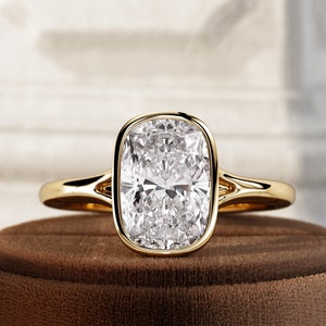 May include: A gold engagement ring with a large, cushion-cut diamond.