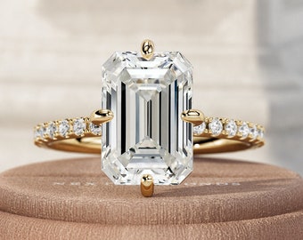May include: A gold engagement ring with a large, clear emerald-cut diamond and a band of smaller diamonds.
