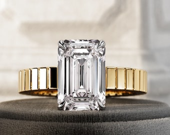 May include: A gold band ring with a large, clear, emerald-cut diamond.