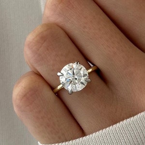 Pu&ograve; includere: Un anello di fidanzamento in oro con un grande diamante rotondo e chiaro.
