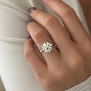 Pu&ograve; includere: Un anello d'oro con un grande diamante rotondo e trasparente.
