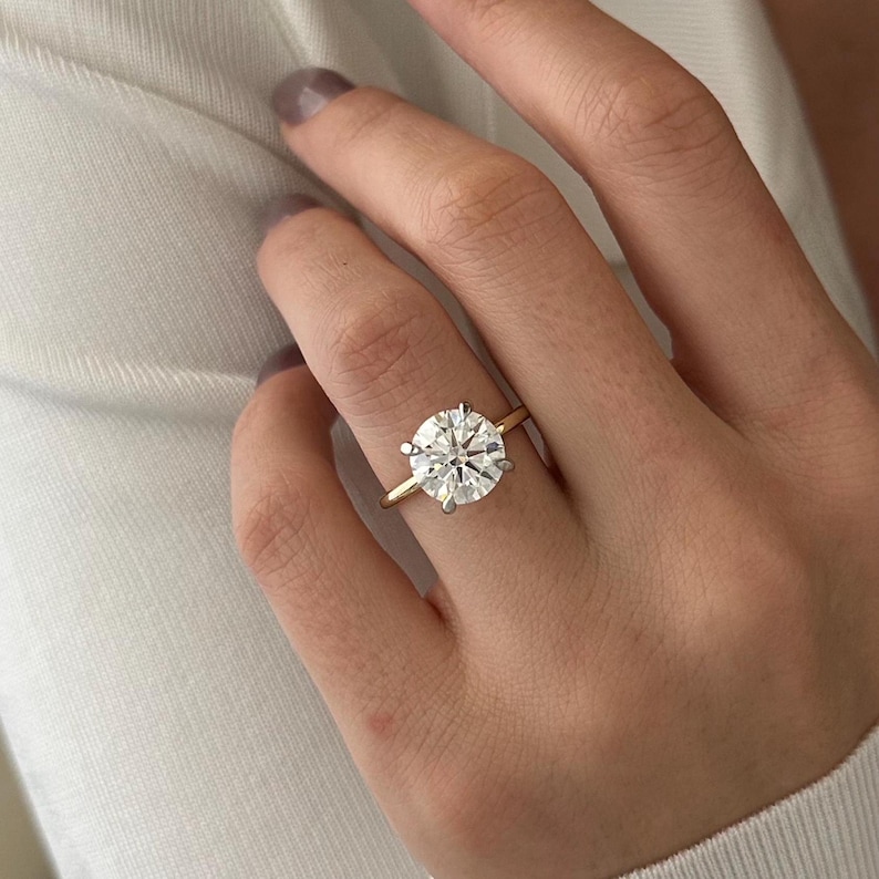 Pu&ograve; includere: Un anello d'oro con un grande diamante rotondo e trasparente.