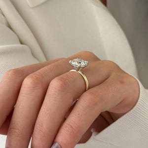 Pu&ograve; includere: Un anello di fidanzamento in oro con un grande diamante ovale trasparente incastonato a griffe.