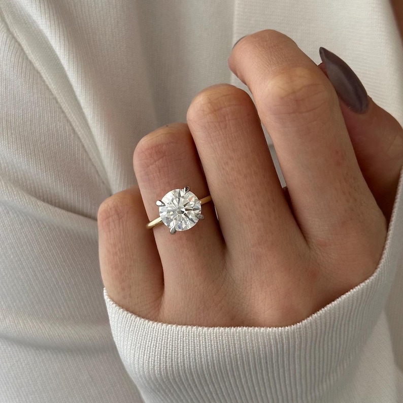 Pu&ograve; includere: Un anello di fidanzamento con fascia dorata e un grande diamante rotondo e chiaro.