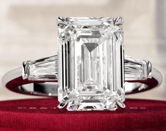 May include: A silver engagement ring with a large, clear emerald-cut diamond and two smaller baguette-cut diamonds on the band.