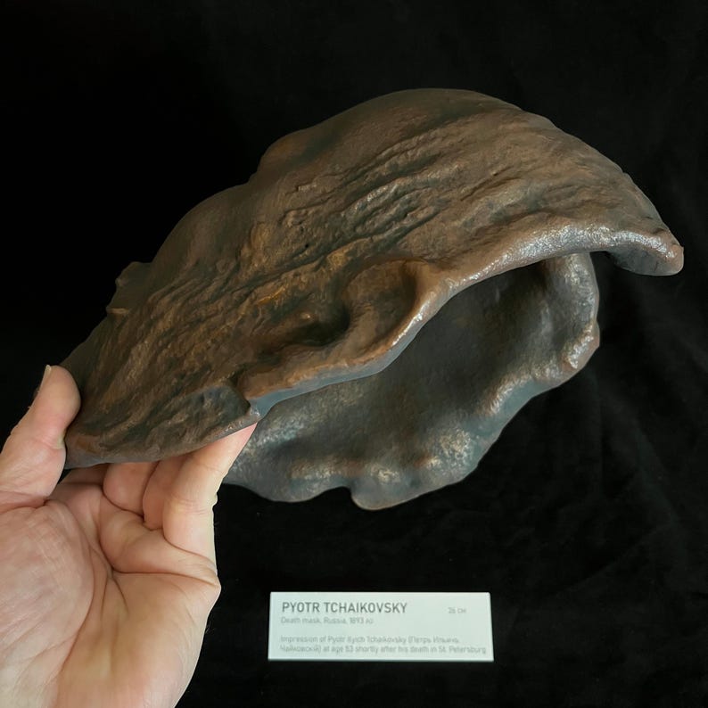 Puede incluir: Una escultura de color bronce con una superficie texturizada, sostenida por una mano. La escultura tiene una forma org&aacute;nica con una gran abertura. Una etiqueta en la parte inferior dice "PYOTR TCHAIKOVSKY".