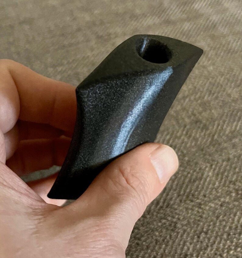 Puede incluir: Una pipa de piedra negra tallada a mano con una superficie redonda y lisa y un agujero en la parte superior para fumar.