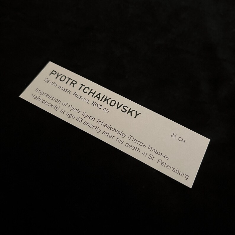 Puede incluir: Una etiqueta rectangular blanca con el texto "PYOTR TCHAIKOVSKY" y "Death mask, Russia, 1893 AD". La etiqueta tambi&eacute;n incluye el texto "Impression of Pyotr Ilyich Tchaikovsky" y "26 cm".