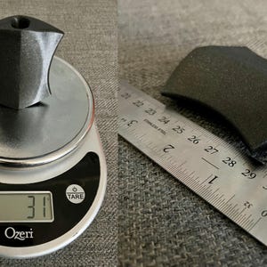 Puede incluir: Una manija de pl&aacute;stico negro con un agujero en el lateral, que pesa 31 gramos. La manija se mide con una regla, mostrando que tiene 7 cm de largo.