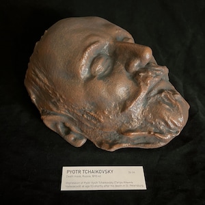 Puede incluir: M&aacute;scara mortuoria de bronce de Pyotr Tchaikovsky, Rusia, 1893. La m&aacute;scara muestra una impresi&oacute;n detallada del rostro del compositor. La etiqueta indica que la m&aacute;scara mide 26 cm de largo. Artefacto hist&oacute;rico.