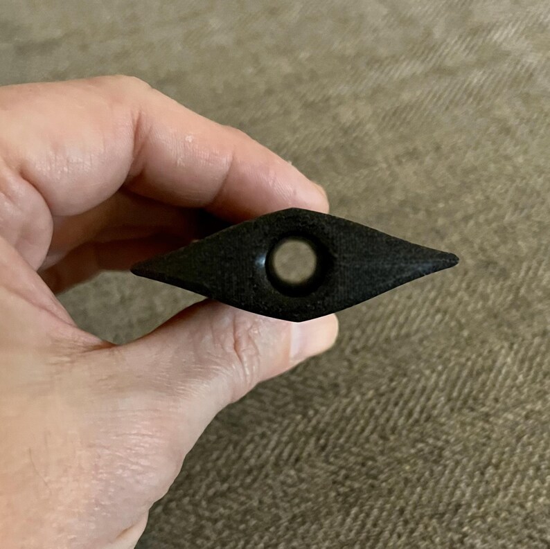 Puede incluir: Una pipa de madera negra en forma de diamante con un agujero redondo en el centro.