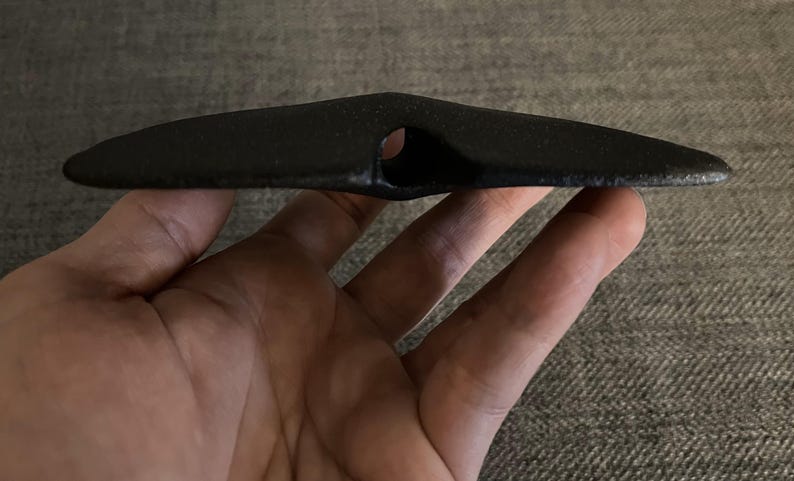 May include: A black ceramic object with a hole in the center, resembling a flying saucer.