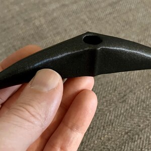 以下が含まれることがあります： 中央に小さな穴のある、鳥のくちばしのような形をした黒い陶器のパイプ