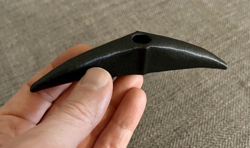 以下が含まれることがあります： 中央に小さな穴のある、鳥のくちばしのような形をした黒い陶器のパイプ