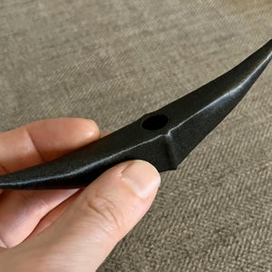 以下が含まれることがあります： 中央に小さな穴のある三日月形の黒い陶器のオブジェクトです。