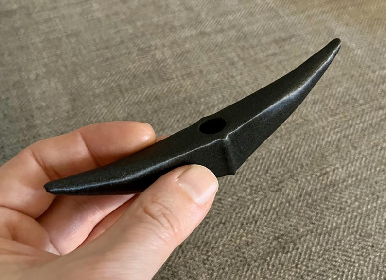 以下が含まれることがあります： 中央に小さな穴のある三日月形の黒い陶器のオブジェクトです。