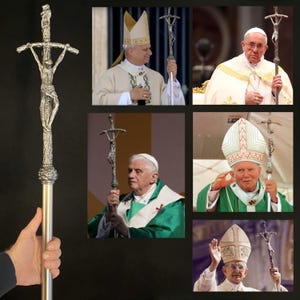 May include: A silver-colored processional cross with a detailed depiction of Jesus Christ on the cross. The cross is held by a person in the image. The image also shows several popes holding the same cross during religious ceremonies.