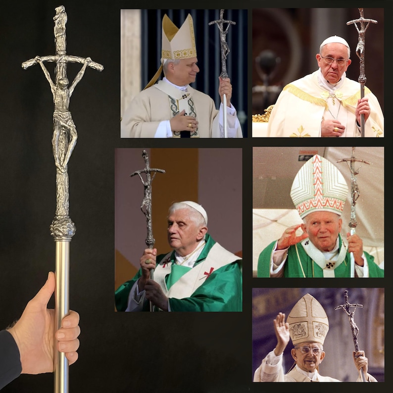 May include: A silver-colored processional cross with a detailed depiction of Jesus Christ on the cross. The cross is held by a person in the image. The image also shows several popes holding the same cross during religious ceremonies.