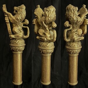 May include: Five antique gold-coloured walking stick handles. Each handle features a detailed lion sculpture atop a column-shaped shaft. The lion sculptures hold various emblems, including a shield and a crown, showcasing intricate craftsmanship.
