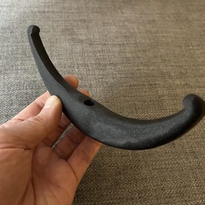 May include: A black metal hook with a curved design. The hook is made of a durable material and has a smooth finish.