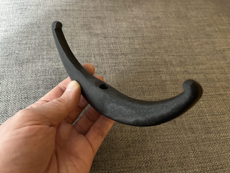 May include: A black metal hook with a curved design. The hook is made of a durable material and has a smooth finish.