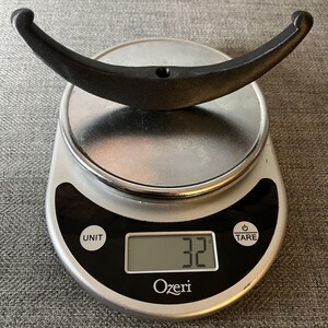 May include: A black metal hook weighing 32 grams on a digital kitchen scale.