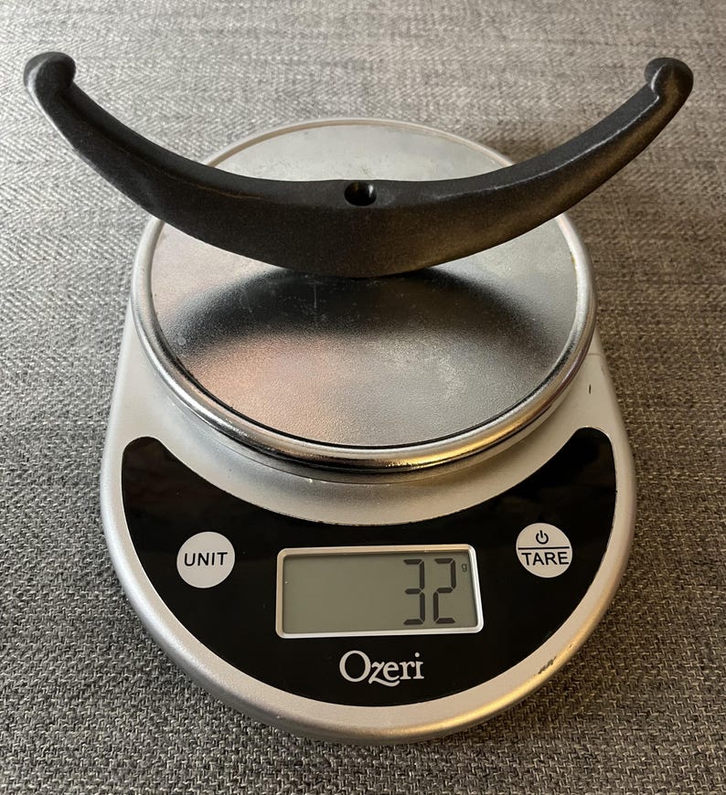 May include: A black metal hook weighing 32 grams on a digital kitchen scale.