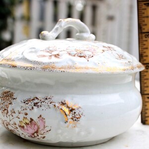May include: White porcelain soap dish with a lid and a floral design in brown, pink, and gold. The lid has a handle.