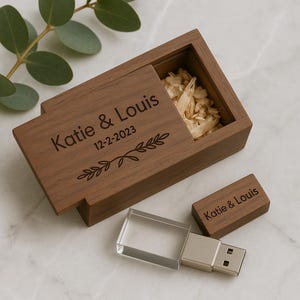 Könnte beinhalten: Eine Holzbox mit Schiebedeckel, graviert mit "Katie & Louis" und dem Datum 12-2-2023, enthält geschreddertes Papier. Ein USB-Stick mit klarer Kunststoffabdeckung und ein USB-Stick aus Holz mit der gleichen Gravur sind ebenfalls vorhanden.