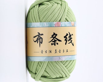 May include: A ball of green yarn with a label that reads "布条线" in Chinese characters. The label also has the text "— 舒适生活 温暖 手工 —" in Chinese characters.