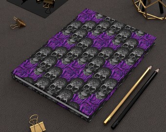 May include: A purple and black notebook with a skull and rose pattern. The notebook is closed and lying on a gray surface.
