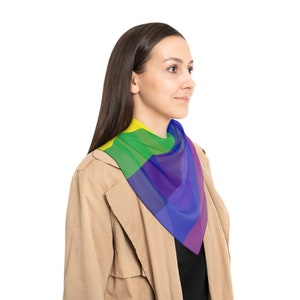 May include: A person wearing a tan coat with a rainbow patterned scarf around their neck.