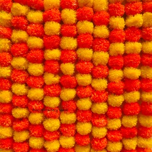 Puede incluir: Una guirnalda de flores de caléndula amarillas y naranjas. La guirnalda está hecha de papel y es una decoración tradicional india.