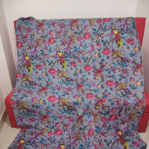 Puede incluir: Una colcha kantha gris con un patrón floral y de pájaros. La colcha está hecha de algodón y tiene un diseño cosido a mano. La colcha es perfecta para agregar un toque de estilo bohemio a tu hogar.
