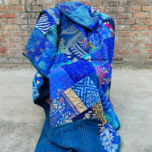 May include: A vibrant blue patchwork quilt with various patterns and textures. The quilt features a mix of floral, geometric, and abstract designs in shades of blue, teal, and indigo. The text "Pics of Mastery India" is visible.