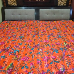 May include: Orange kantha quilt with a floral and bird pattern. The quilt is made of cotton and has a hand-stitched design.