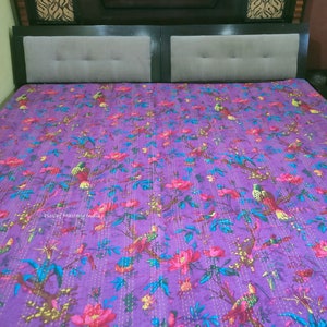 May include: Purple kantha quilt with a floral and bird pattern. The quilt is hand-stitched with yellow thread and features a variety of colors, including pink, green, and blue.