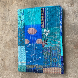 May include: A patchwork quilt made of various blue and green fabrics with a floral pattern. The quilt is hand-stitched and has a unique, rustic look. The text "Pics of mastery India" is visible in the bottom right corner.