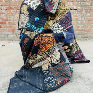 May include: A patchwork quilt with a variety of patterned fabric squares in shades of black, blue, red, orange, and gold. The quilt is folded, revealing the intricate stitching and the reverse side of the quilt. The text "Pics of Mastery India" is visible.
