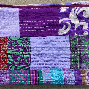 Può includere: Un quilt patchwork viola e verde con un design floreale bianco. Il quilt è realizzato con sari riciclati ed è cucito a mano. Il quilt misura circa 152 cm per 203 cm.