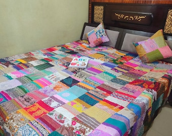 May include: A colorful patchwork quilt with a variety of fabrics and patterns. The quilt is made up of squares and rectangles of different colors and designs. The quilt is on a bed with pillows and a book on top of it.