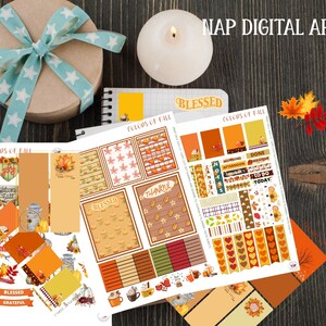May include: A collection of fall-themed digital planner stickers and stationery. The designs include pumpkins, leaves, and the text "COLORS OF FALL", "BLESSED", and "THANKFUL". A gift box with a blue ribbon and a lit candle are also present.
