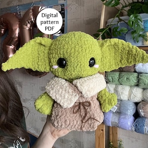 Könnte beinhalten: Ein handgefertigtes grünes Plüschtier mit großen Ohren, schwarzen Augen und einem beigefarbenen Outfit. Das Spielzeug hat einen cremefarbenen Kragen und eine braune Krawatte. Der Text "Digital pattern PDF" befindet sich in einem weißen Kreis. Das Spielzeug wird von einer Person gehalten.