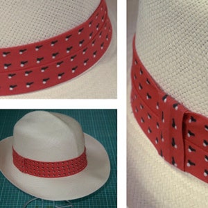 May include: A white straw hat with a red and black patterned band. The band has a repeating pattern of small black shapes on a red background.