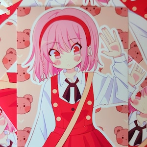 May include: A colorful anime-style illustration of a girl with pink hair and red eyes, wearing a red dress and white shirt. She is waving with one hand. The background features a pattern of teddy bears. A beige satchel is over her shoulder.