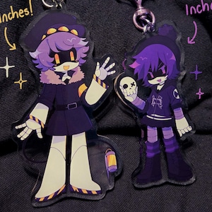 May include: Two acrylic keychains featuring anime-style characters. One is 4 inches tall, the other is 3.5 inches. The characters have purple hair and wear dark clothing. Each keychain has a bat-shaped clasp.