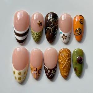 May include: A set of ten press-on nails featuring various designs including brown and white stripes, a ladybird on a green base, dark brown swirls, floral patterns, orange with gold spirals, gold dots, geometric shapes, and textured brown and green finishes.