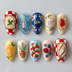 May include: A collection of ten artificial nails with detailed food-themed designs. The designs include a slice of toast with basil, a bottle of water, olives, a label with text, a slice of toast with jam, a slice of orange, a potted plant, tomatoes and mozzarella, and berries.
